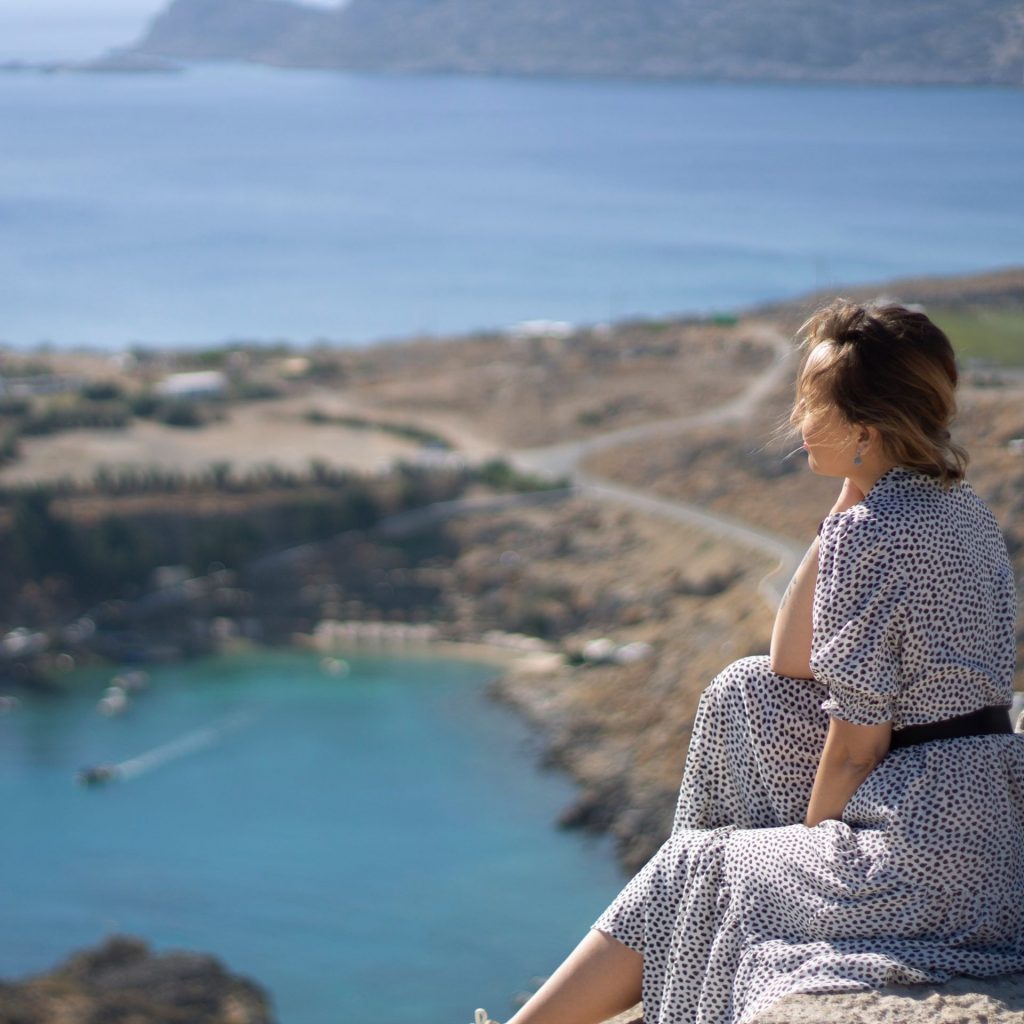 A woman enjoy view of lake sitting on a hill