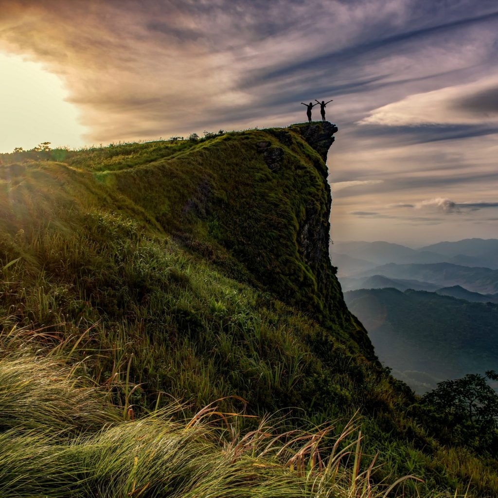 Two girls stand top up hill and enjoy sunset