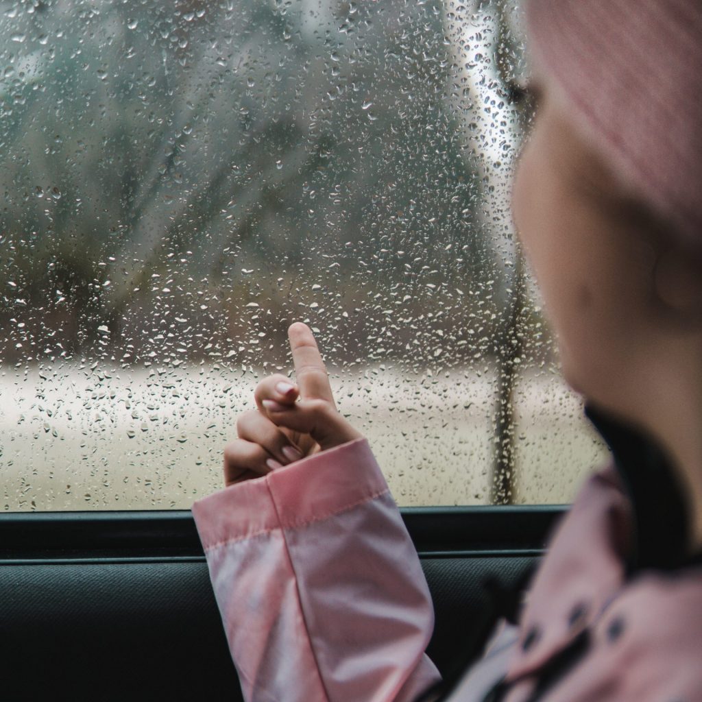 A girl enjoy the rain seating in the car whatsapp dp image