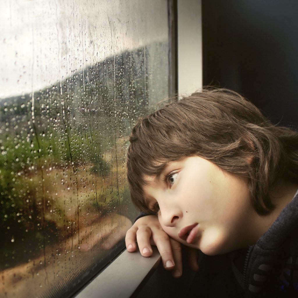 A little boy enjoy the rain seating in home whatsapp dp image