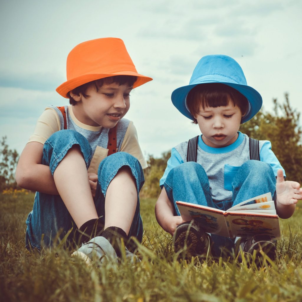 Two Boys Reading Book In The Grass Field Whatsapp Dp Image